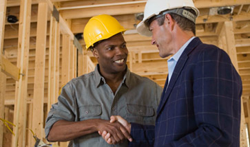 Two men in hard hats speaking on construction site
